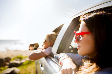 Image showing happy teenage girls or women in car at seaside