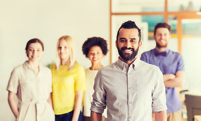 Image showing happy young man over creative team in office