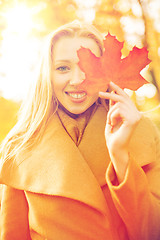 Image showing woman with red marple leaf in the autumn park