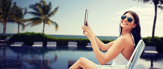 Image showing smiling woman with tablet pc sunbathing on beach