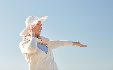 Image showing happy senior woman in sun hat over blue sky