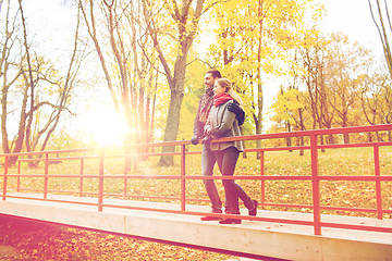 Image showing smiling couple hugging on bridge in autumn park