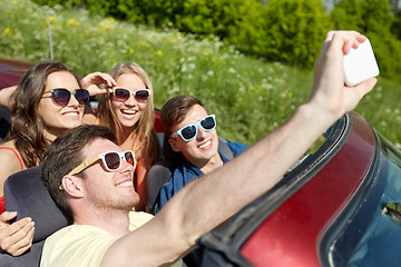 Image showing friends driving in cabriolet car and taking selfie