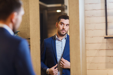 Image showing man trying jacket on at mirror in clothing store