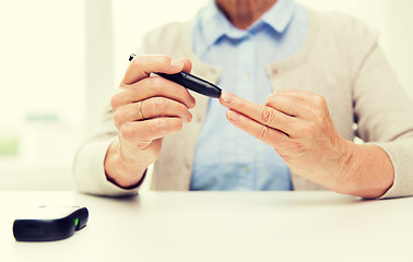 Image showing senior woman with glucometer checking blood sugar