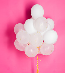 Image showing close up of white helium balloons over pink