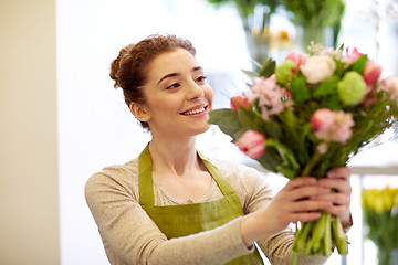 Image showing smiling florist woman making bunch at flower shop