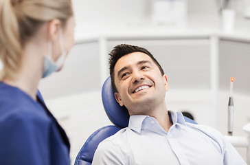 Image showing female dentist with happy male patient at clinic