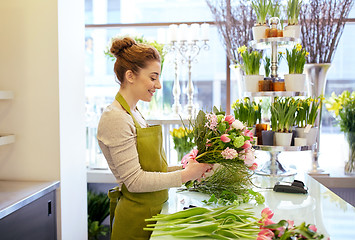 Image showing smiling florist woman making bunch at flower shop