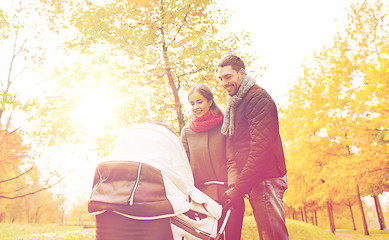 Image showing smiling couple with baby pram in autumn park