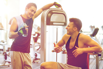 Image showing smiling men exercising on gym machine