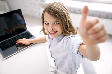 Image showing smiling girl with laptop showing thumbs up at home