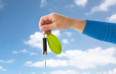 Image showing close up of hand holding car key with green leaf