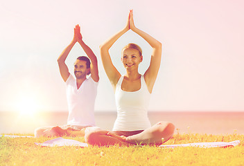 Image showing smiling couple making yoga exercises outdoors