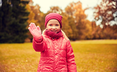 Image showing happy little girl waving hand in autumn park