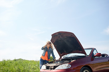 Image showing woman with open hood of broken car at countryside