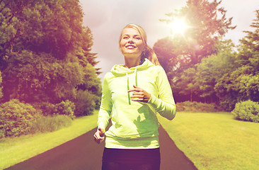 Image showing happy smiling young woman jogging outdoors