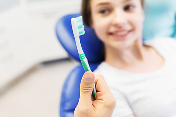 Image showing close up of dentist hand with toothbrush and girl