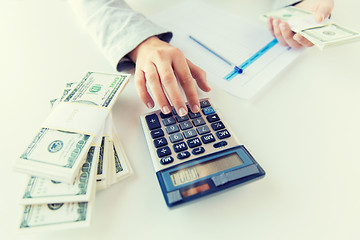 Image showing close up of hands counting money with calculator