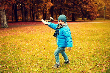 Image showing happy little boy playing with toy plane outdoors