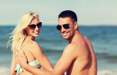 Image showing happy couple in swimwear sitting on summer beach