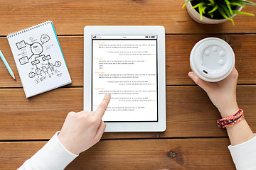 Image showing close up of woman with tablet pc on wooden table