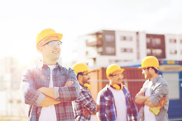 Image showing group of smiling builders in hardhats outdoors