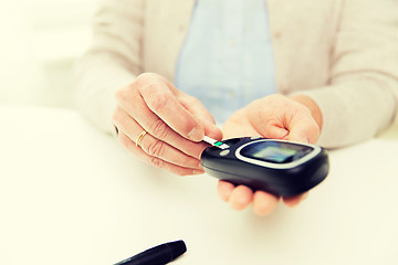 Image showing senior woman with glucometer checking blood sugar