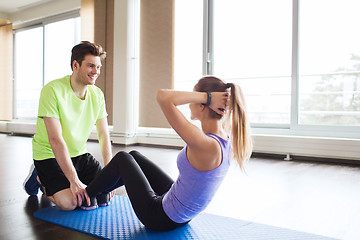 Image showing woman with personal trainer doing sit ups in gym