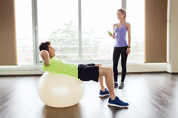 Image showing smiling man and woman with exercise ball in gym