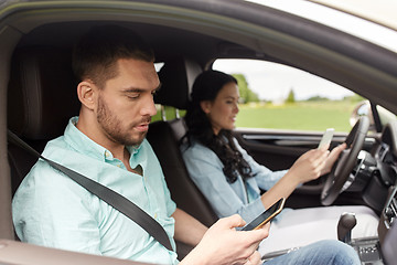 Image showing man and woman with smartphones driving in car