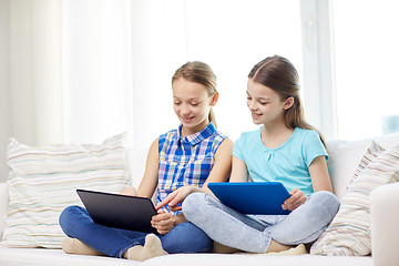 Image showing happy girls with tablet pc sitting on sofa at home