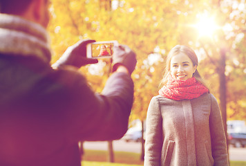 Image showing smiling couple with smartphone in autumn park