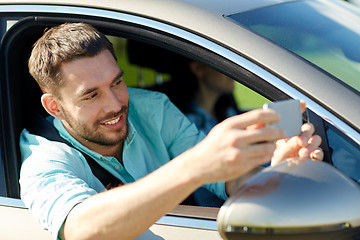 Image showing happy smiling man with smartphone driving in car