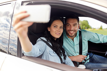 Image showing happy couple in car taking selfie with smartphone