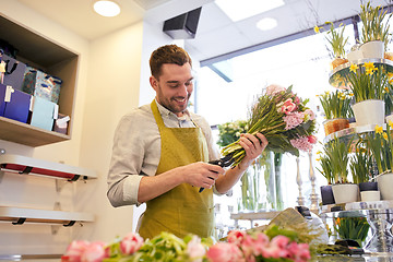 Image showing smiling florist man making bunch at flower shop