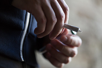 Image showing close up of addict hands with marijuana joint tube