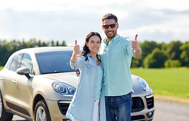 Image showing happy man and woman showing thumbs up at car