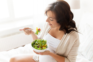 Image showing happy pregnant woman eating salad at home