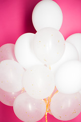 Image showing close up of white helium balloons over pink