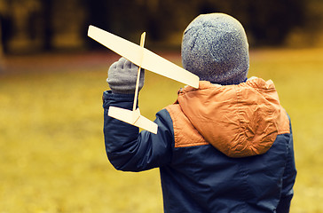 Image showing happy little boy playing with toy plane outdoors