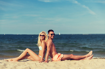 Image showing happy couple in swimwear sitting on summer beach