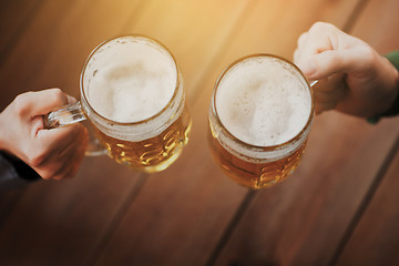 Image showing close up of hands with beer mugs at bar or pub