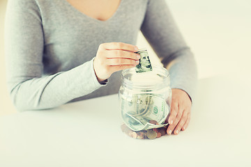 Image showing close up of woman hands and dollar money in jar