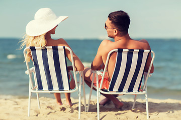 Image showing happy couple sunbathing in chairs on summer beach