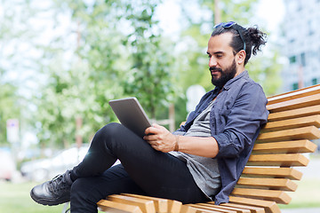 Image showing man with tablet pc sitting on city street bench