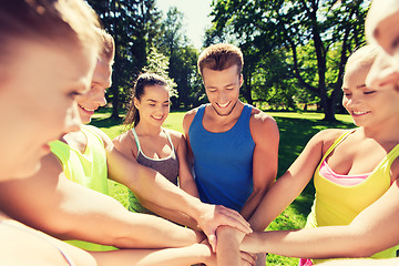 Image showing group of happy friends with hands on top outdoors