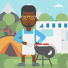 Image showing Man having barbecue in front of camper van.