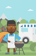Image showing Man having barbecue in front of camper van.