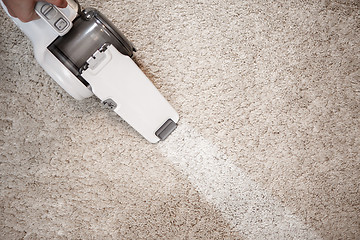 Image showing Top view of cordless handheld vacuum cleaner on beige carpet
